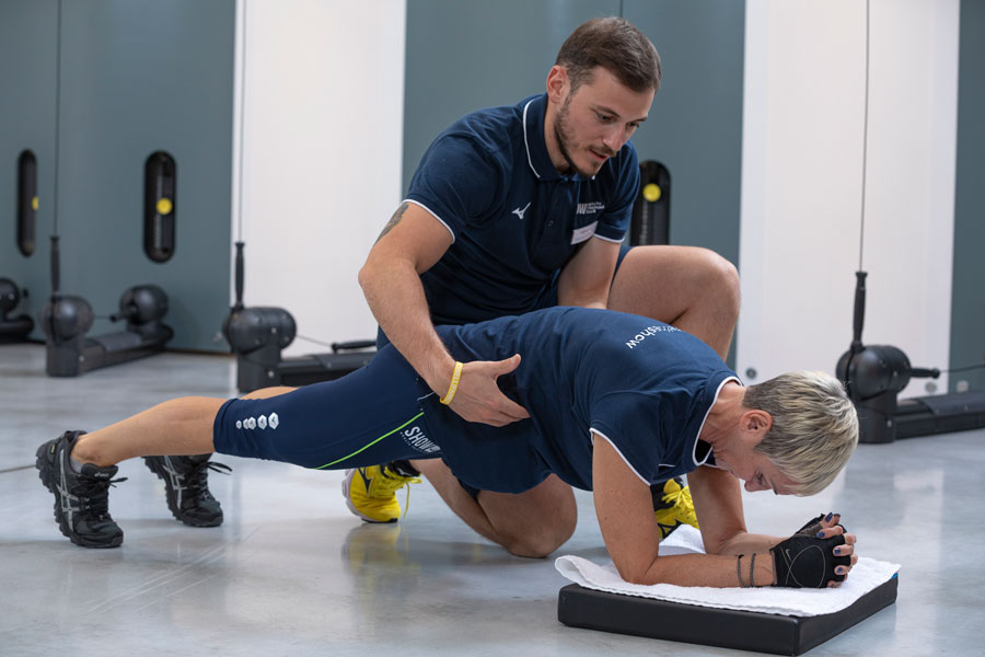 mujer sonriente entrenando con un entrenador personal en el gimnasio