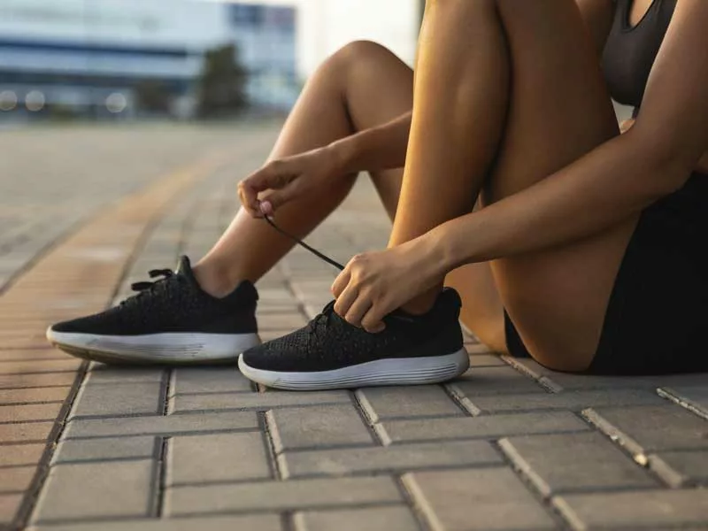 Mujer comenzando a hacer actividad física y atándose las zapatillas
