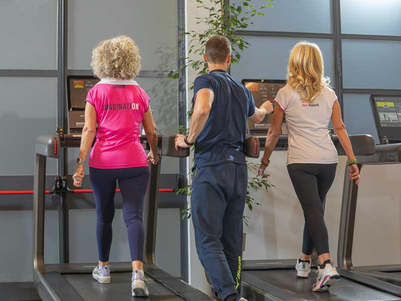 Entrenador personal guiando entrenamiento grupal ajustando parámetros personalizados