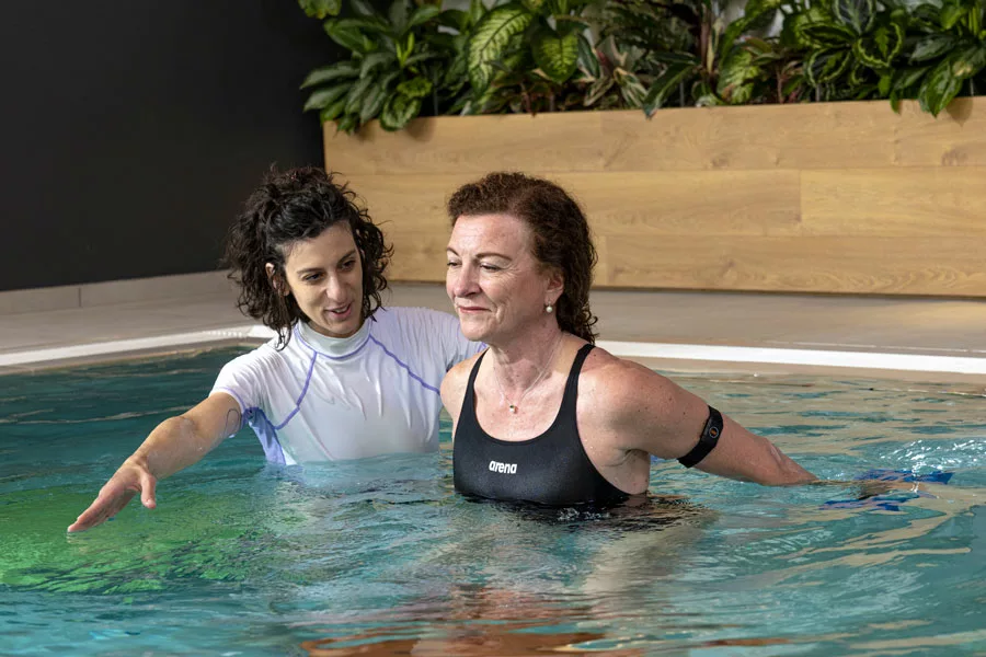 mujer realiza ejercicios en el agua para la espalda con la ayuda de un entrenador personal