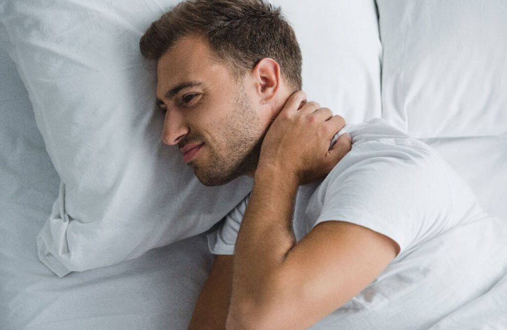 Hombre con dolor en el cuello en la cama