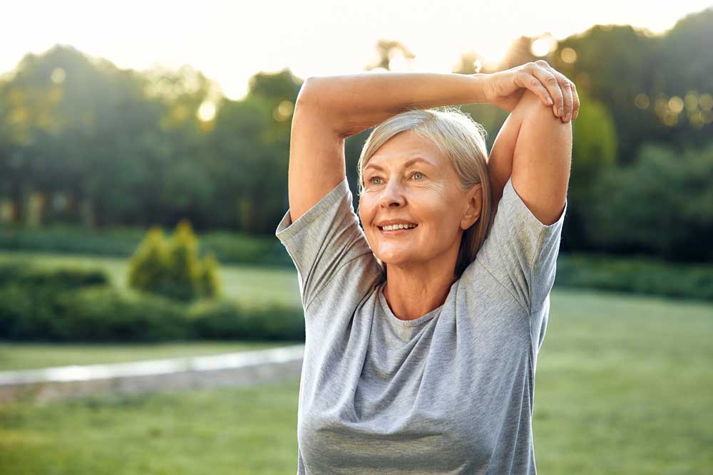 mujer haciendo ejercicios de gimnasia postural en el parque y está feliz