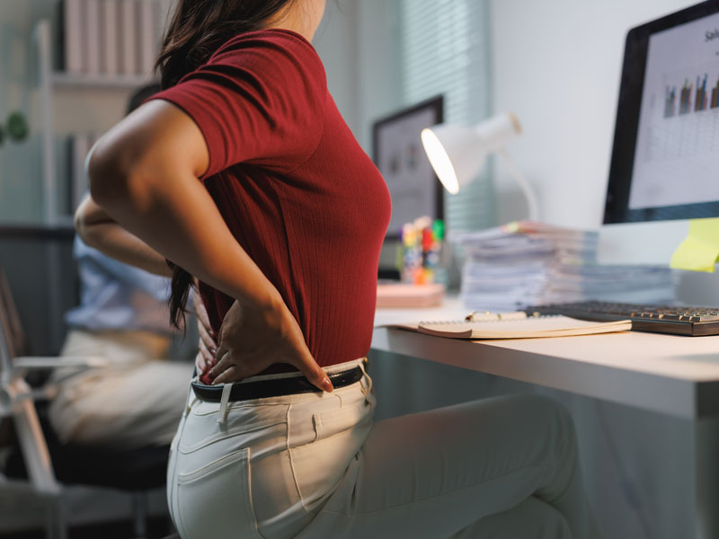 Mujer con dolor de espalda en el escritorio