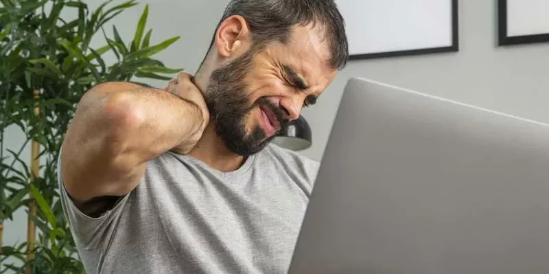 Hombre sentado en la oficina por horas, con dolor en el cuello